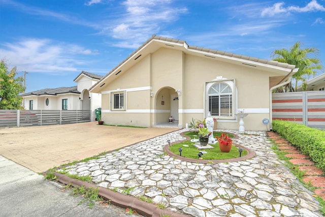 view of front of home with driveway, a tiled roof, fence, and stucco siding