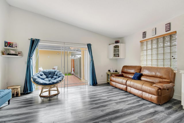 living room featuring lofted ceiling, baseboards, and wood finished floors