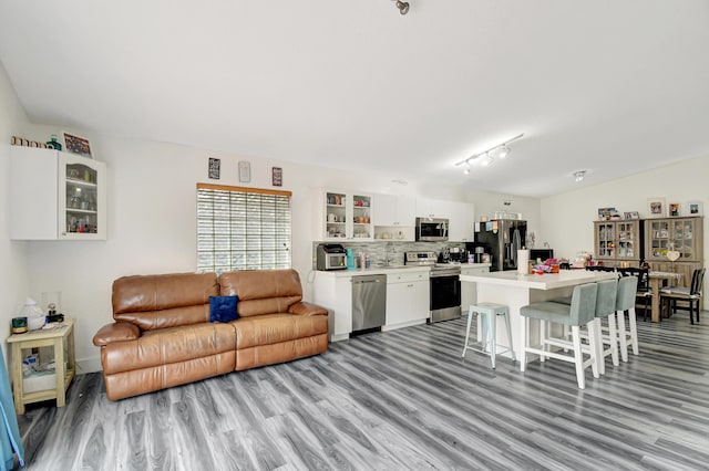 kitchen with light countertops, appliances with stainless steel finishes, glass insert cabinets, white cabinetry, and a kitchen bar