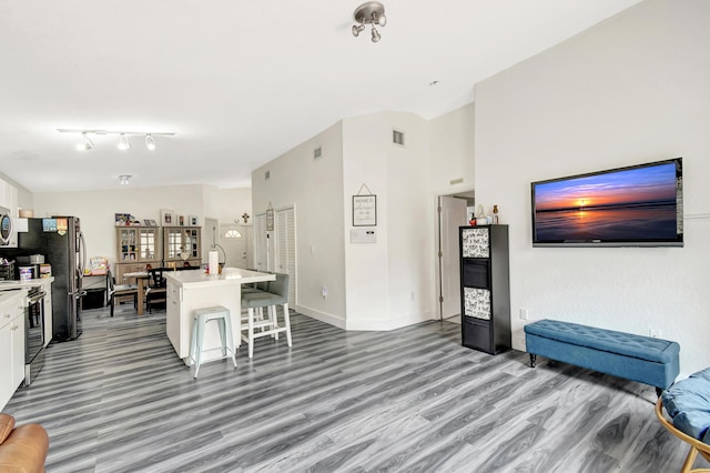 kitchen featuring lofted ceiling, a kitchen island with sink, white cabinetry, light countertops, and a kitchen bar