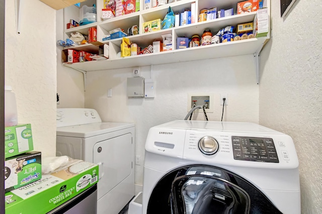 laundry area featuring laundry area, a textured wall, and washing machine and clothes dryer