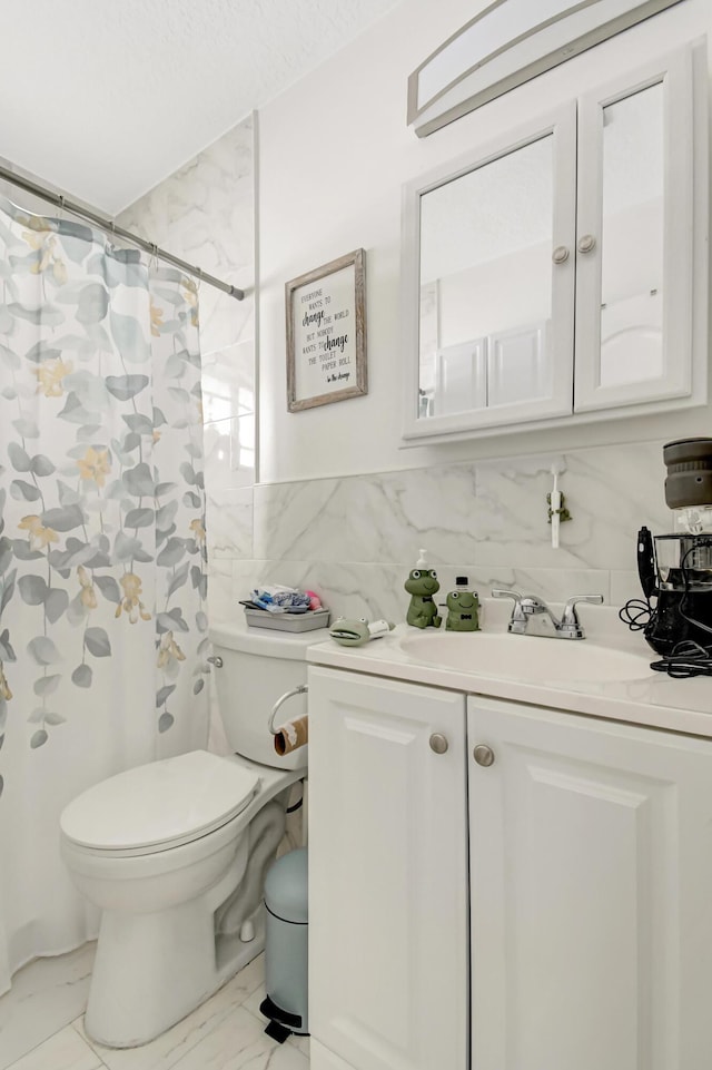 full bath featuring toilet, a shower with shower curtain, vanity, tile walls, and marble finish floor