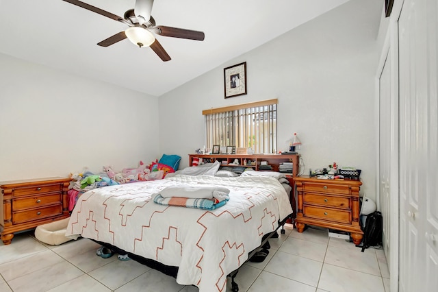 bedroom with a ceiling fan, lofted ceiling, a closet, and light tile patterned flooring