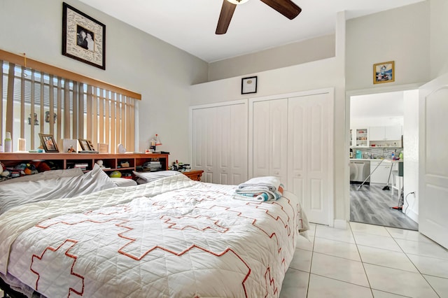 bedroom with light tile patterned floors, ceiling fan, a high ceiling, and two closets