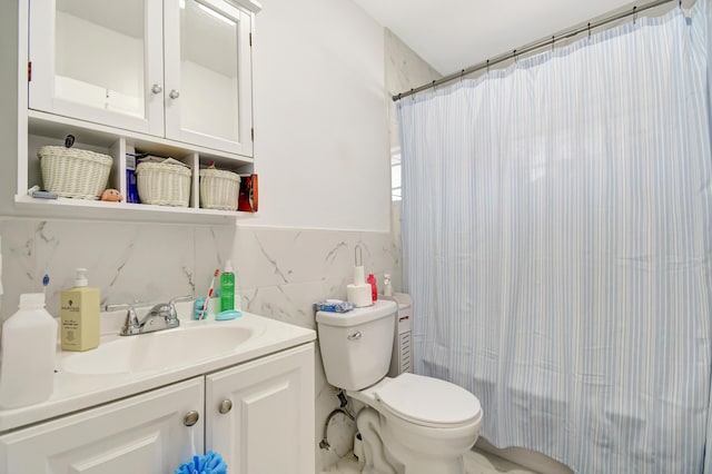 bathroom featuring toilet, vanity, and tile walls