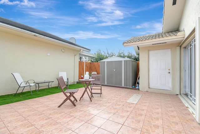 view of patio / terrace with an outbuilding, a storage unit, and fence