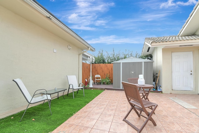 view of patio featuring a storage shed, fence, and an outbuilding