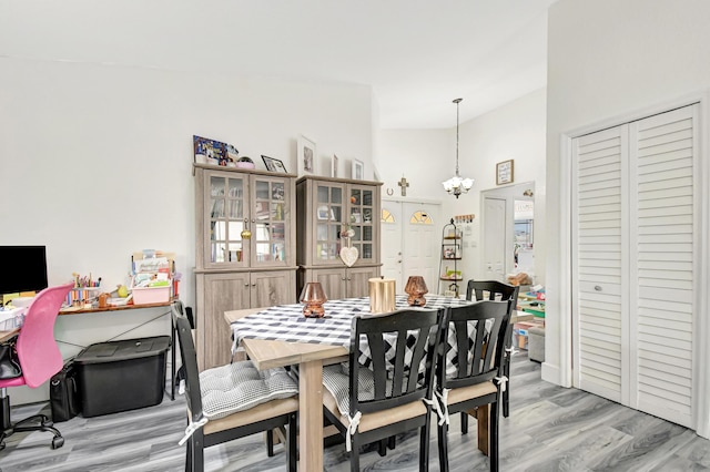 dining space with a chandelier, vaulted ceiling, and wood finished floors