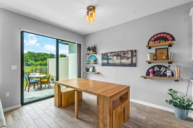 dining area featuring a textured ceiling, baseboards, and wood finished floors