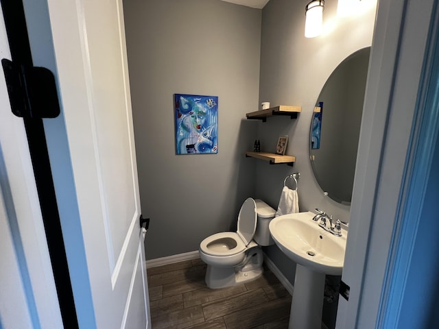 bathroom with toilet, wood tiled floor, baseboards, and a sink