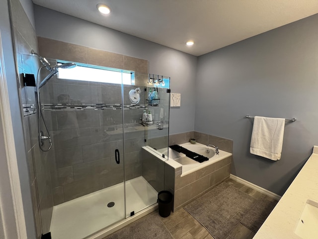 bathroom with a shower stall, baseboards, a bath, and vanity