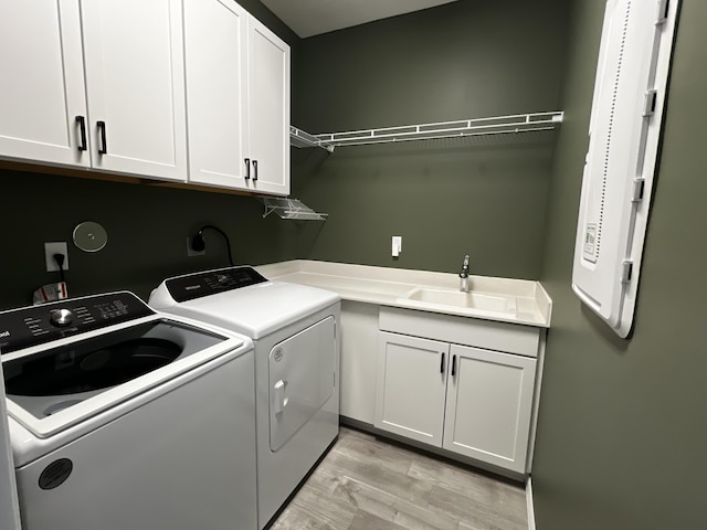 clothes washing area featuring cabinet space, light wood-style floors, separate washer and dryer, and a sink