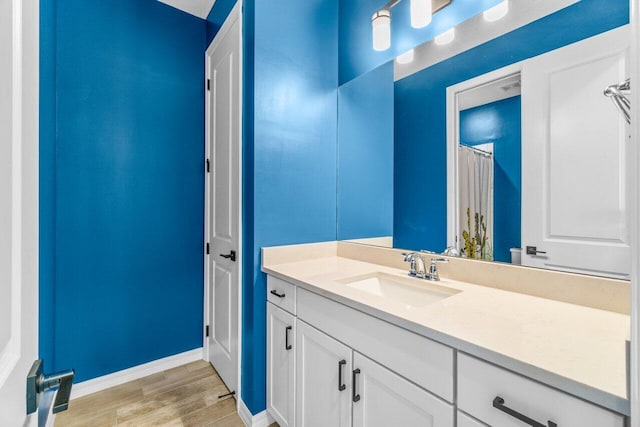 full bath featuring wood finished floors, vanity, and baseboards