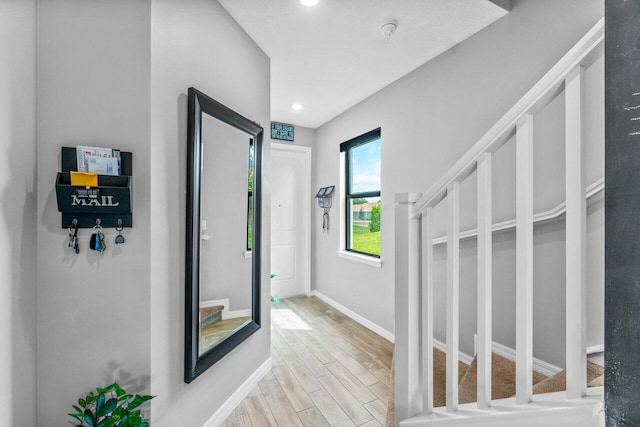 hallway with stairs, recessed lighting, light wood-style flooring, and baseboards