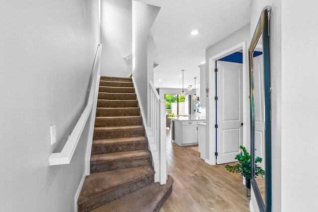 staircase with recessed lighting and wood finished floors