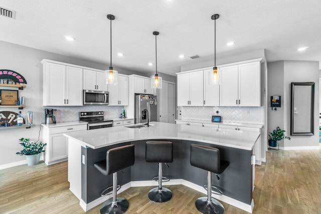 kitchen featuring hanging light fixtures, a kitchen island with sink, and appliances with stainless steel finishes