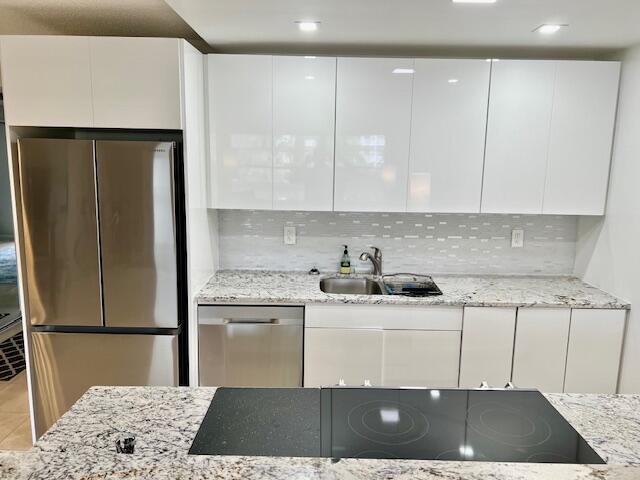 kitchen with light stone countertops, white cabinetry, modern cabinets, and appliances with stainless steel finishes