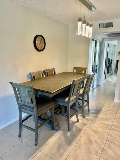 dining room featuring visible vents, a textured ceiling, baseboards, and light tile patterned floors