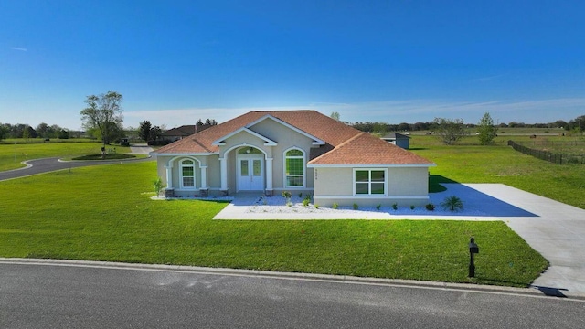 mediterranean / spanish-style house featuring a front yard, concrete driveway, and stucco siding