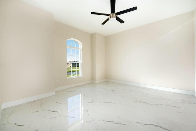 empty room with baseboards, marble finish floor, and a ceiling fan