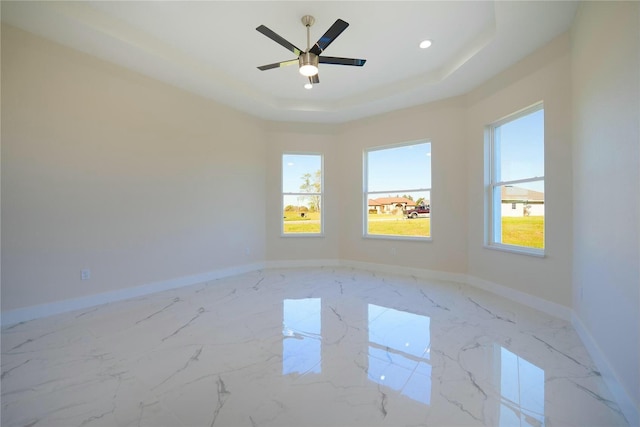 spare room featuring baseboards, a raised ceiling, and marble finish floor