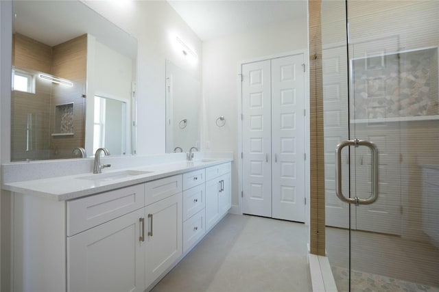 full bathroom featuring double vanity, a stall shower, and a sink