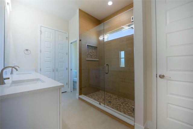 full bath featuring double vanity, a shower stall, toilet, and a sink