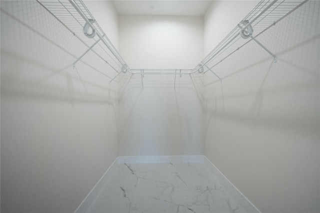 walk in closet featuring marble finish floor