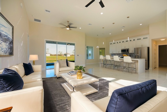 living area with light tile patterned floors, visible vents, and ceiling fan