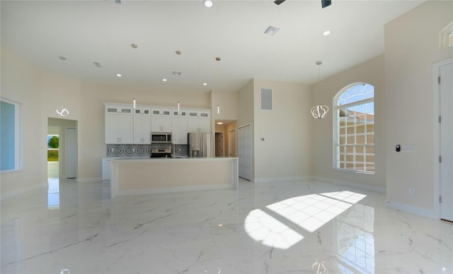 kitchen with visible vents, marble finish floor, a center island with sink, appliances with stainless steel finishes, and baseboards