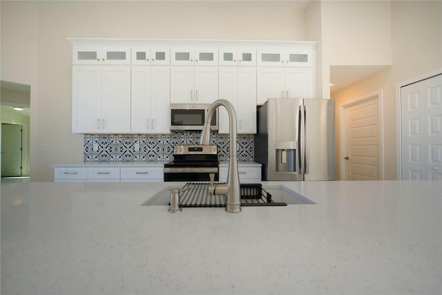 kitchen with tasteful backsplash, white cabinets, and appliances with stainless steel finishes