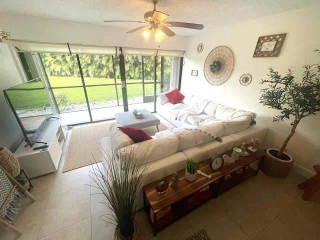 living room with a ceiling fan, a textured ceiling, and light tile patterned floors