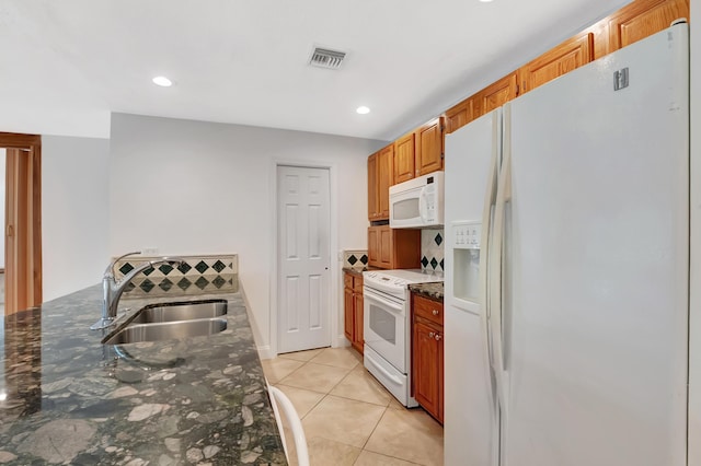 kitchen with light tile patterned flooring, white appliances, a sink, visible vents, and dark stone counters