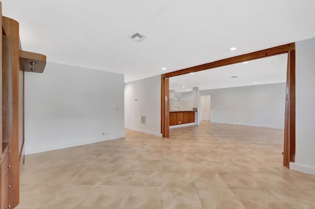 spare room featuring baseboards, a sink, visible vents, and recessed lighting