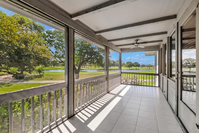 unfurnished sunroom featuring a water view, a ceiling fan, and beamed ceiling