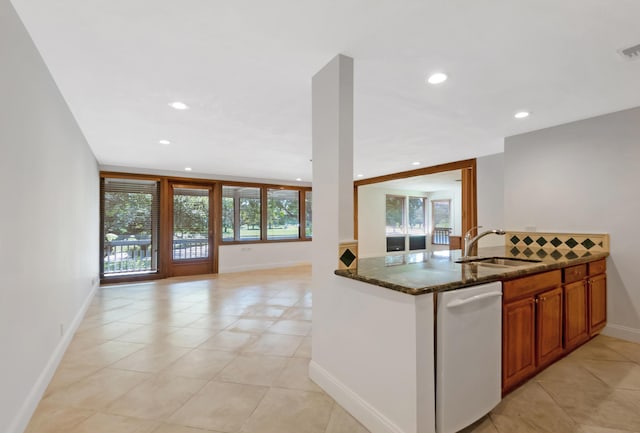 kitchen with a sink, open floor plan, dark stone counters, brown cabinetry, and dishwasher