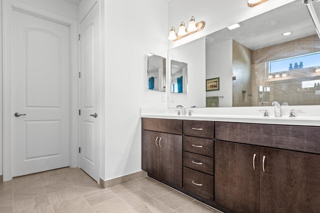 full bath featuring a sink, double vanity, baseboards, and tiled shower