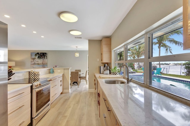 kitchen featuring visible vents, light brown cabinetry, stainless steel range with electric cooktop, light wood-style floors, and a sink