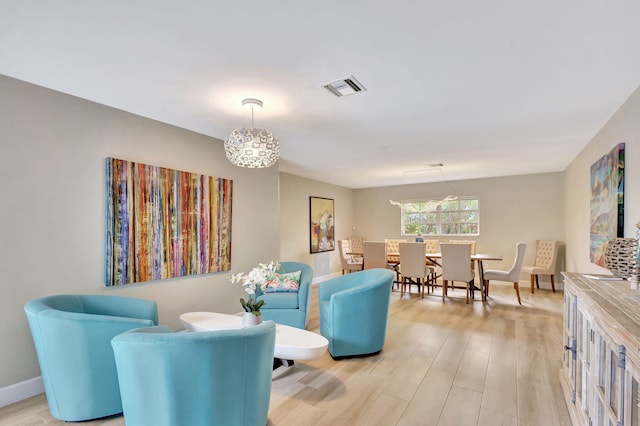 living area with light wood-type flooring, visible vents, and baseboards