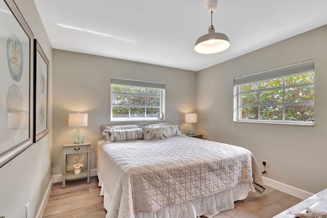 bedroom with light wood-type flooring, multiple windows, and baseboards