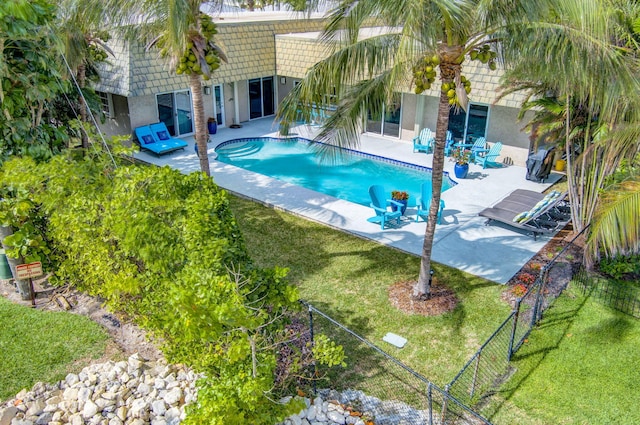 outdoor pool with fence, a lawn, and a patio