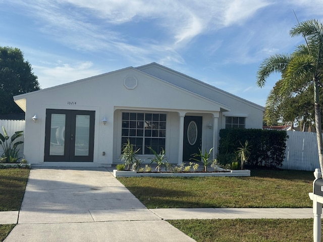 view of front facade with french doors, a front yard, fence, and stucco siding