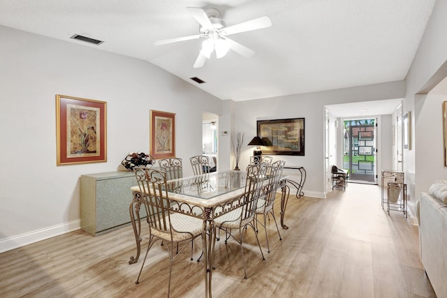 dining room with lofted ceiling, baseboards, visible vents, and light wood finished floors