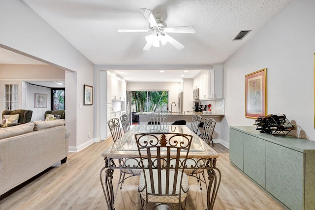 dining room with baseboards, visible vents, ceiling fan, a textured ceiling, and light wood-style floors