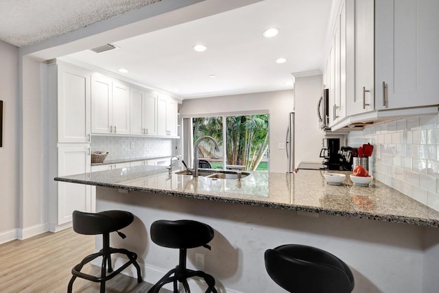 kitchen featuring a peninsula, light stone counters, and white cabinets