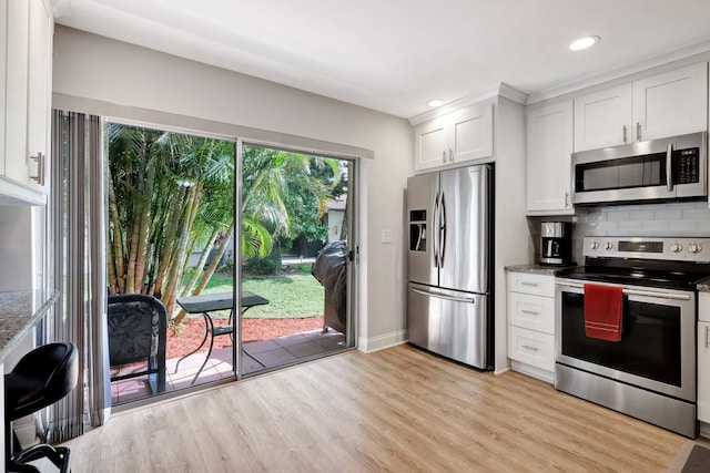 kitchen with stainless steel appliances, white cabinets, backsplash, and dark stone countertops