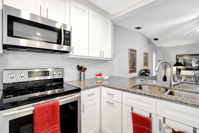 kitchen with light stone counters, appliances with stainless steel finishes, a sink, and white cabinetry