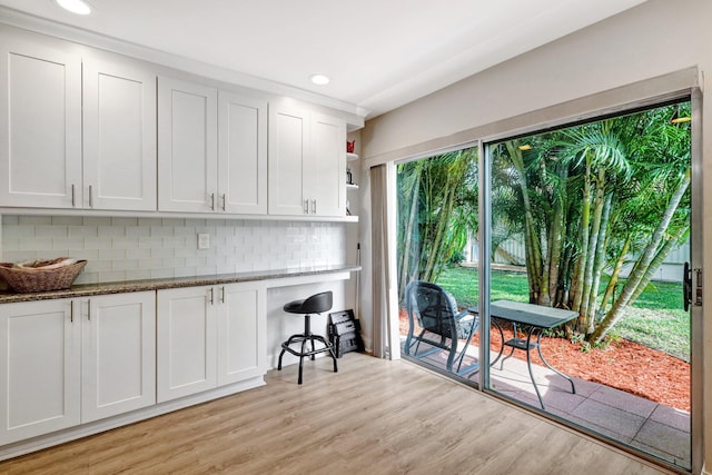 kitchen featuring light wood-style flooring, white cabinetry, open shelves, tasteful backsplash, and dark stone countertops