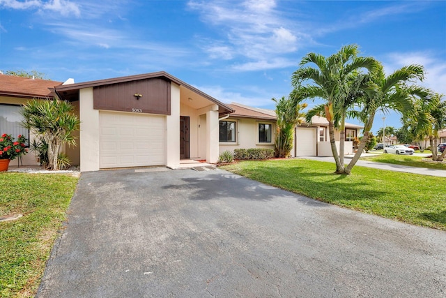 view of front of property featuring a garage, aphalt driveway, a front yard, and stucco siding