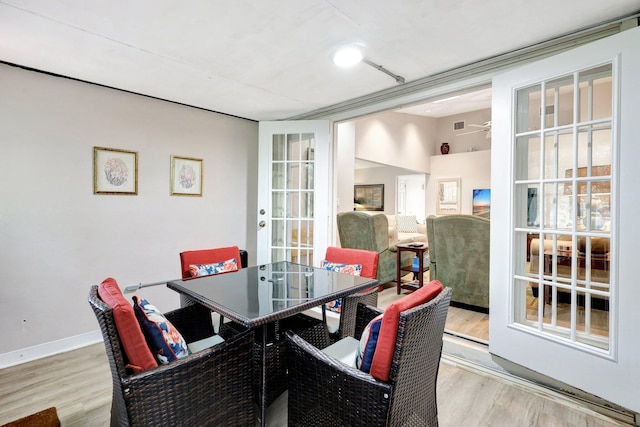 dining room with light wood-style floors, ceiling fan, baseboards, and french doors